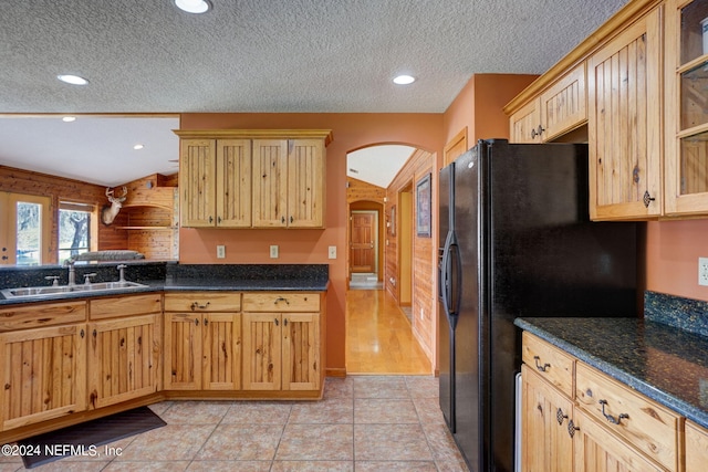 kitchen featuring black refrigerator, a textured ceiling, and light tile flooring