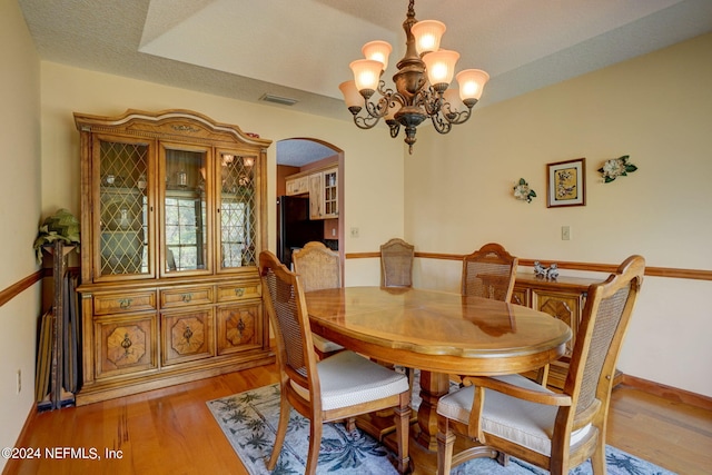 dining room featuring a raised ceiling, light hardwood / wood-style floors, and a notable chandelier