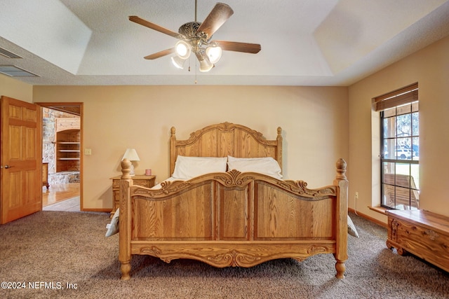 bedroom featuring a raised ceiling, carpet flooring, a textured ceiling, and ceiling fan