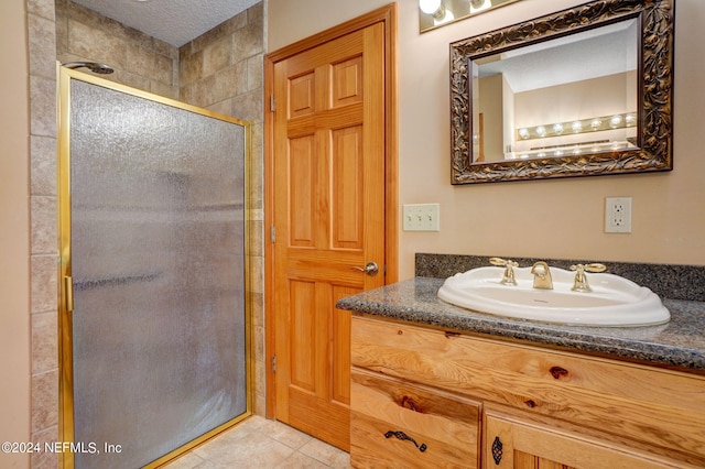 bathroom with oversized vanity, a textured ceiling, a shower with shower door, and tile flooring