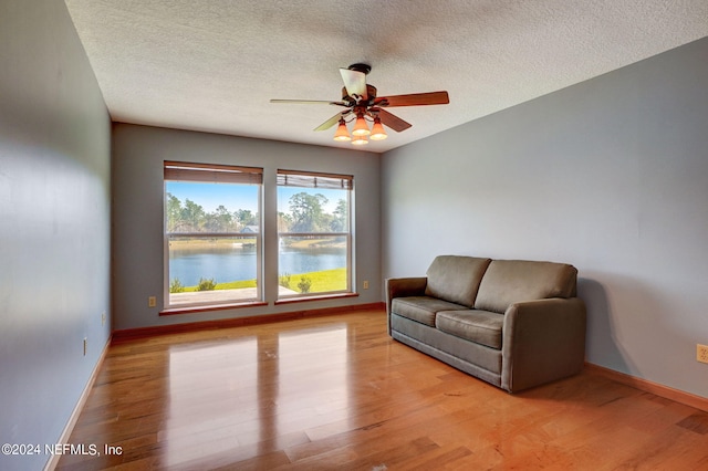 unfurnished room with light hardwood / wood-style flooring, ceiling fan, and a water view