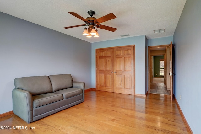 sitting room with a textured ceiling, ceiling fan, and light wood-type flooring