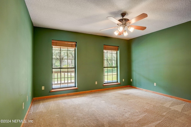 carpeted spare room with plenty of natural light, ceiling fan, and a textured ceiling