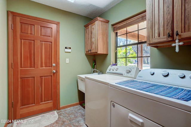 laundry area featuring light tile flooring, a textured ceiling, cabinets, and washer and clothes dryer