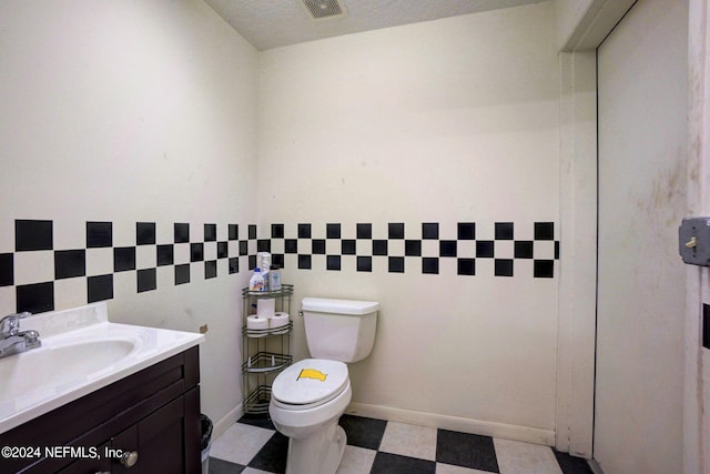 bathroom with tile floors, toilet, vanity, and a textured ceiling