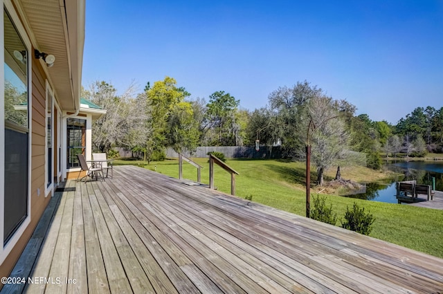 wooden terrace featuring a lawn and a water view