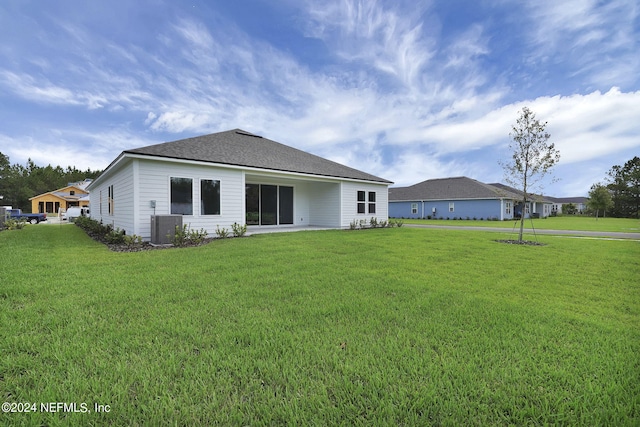 back of house featuring central air condition unit and a yard