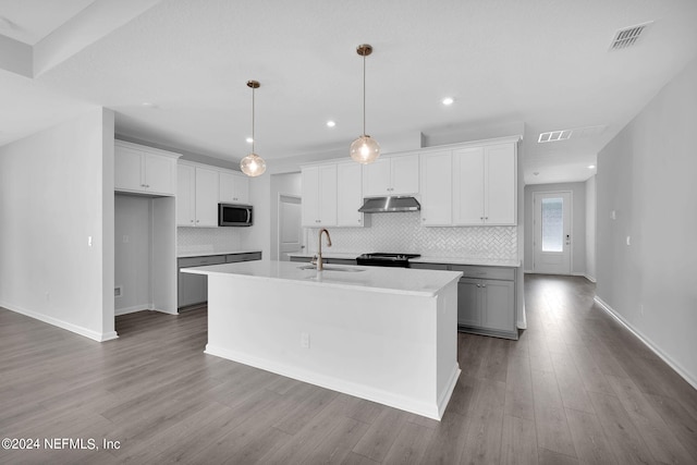 kitchen with a kitchen island with sink, white cabinets, black range oven, sink, and decorative light fixtures