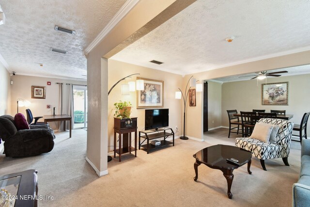 carpeted living room featuring ceiling fan, a textured ceiling, and ornamental molding