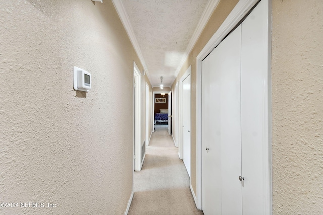 hall with light carpet, a textured ceiling, and ornamental molding