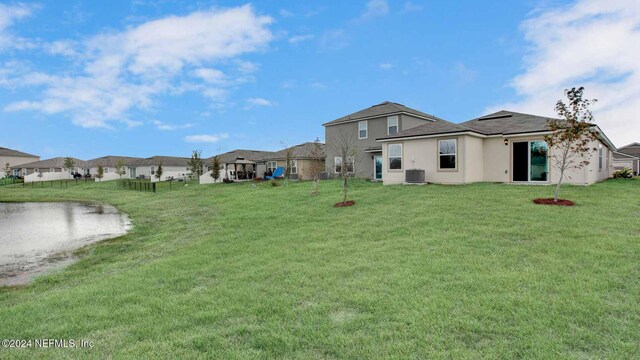 back of house with cooling unit and a lawn