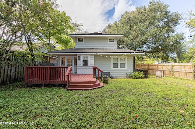 rear view of house with a lawn and a wooden deck