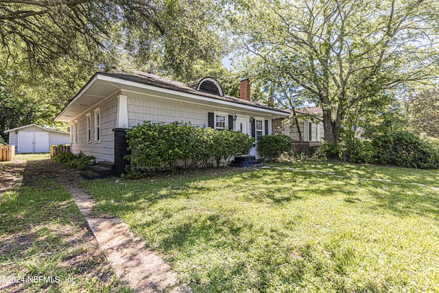 view of front of property with a front lawn and a storage shed