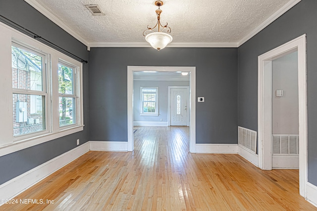 unfurnished room featuring light hardwood / wood-style floors, a textured ceiling, and ornamental molding