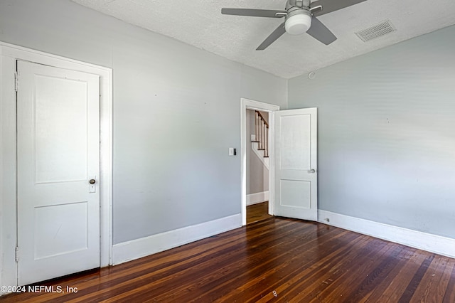 empty room with ceiling fan, a textured ceiling, and dark wood-type flooring