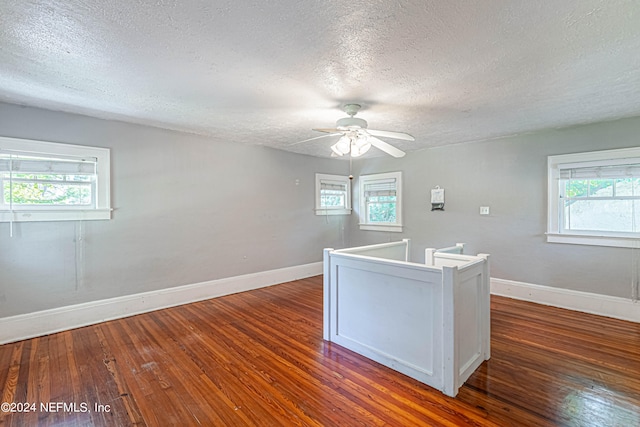 interior space with a healthy amount of sunlight, a textured ceiling, ceiling fan, and dark hardwood / wood-style flooring