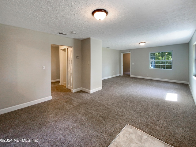 unfurnished room featuring a textured ceiling and dark colored carpet