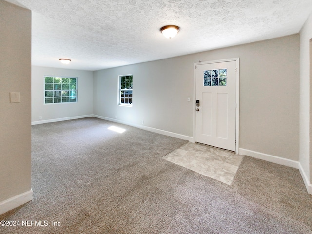 foyer with light colored carpet and a textured ceiling