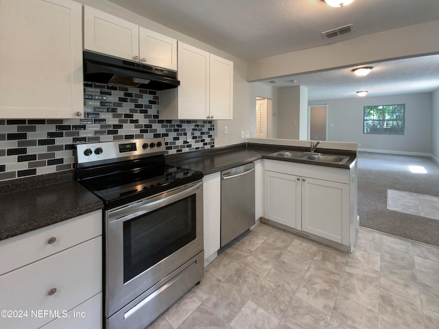 kitchen with kitchen peninsula, appliances with stainless steel finishes, sink, white cabinets, and tasteful backsplash