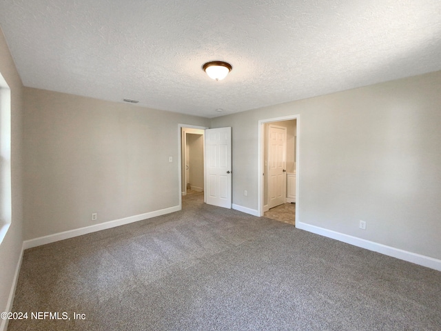 spare room featuring light carpet and a textured ceiling