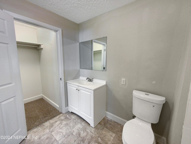 bathroom with toilet, vanity with extensive cabinet space, tile flooring, and a textured ceiling