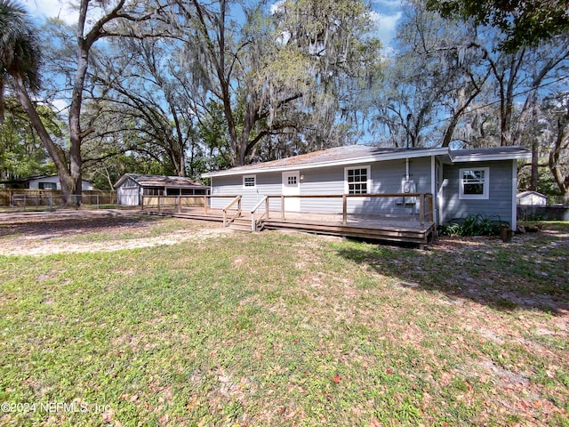 rear view of property with a wooden deck, a lawn, and a shed