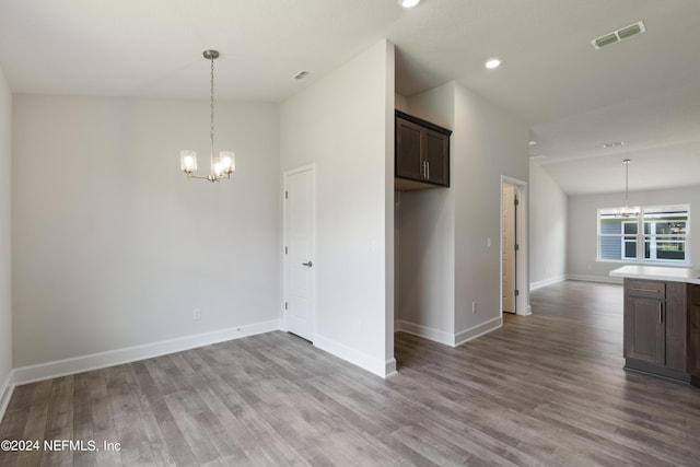 unfurnished room featuring a towering ceiling, light hardwood / wood-style floors, and an inviting chandelier