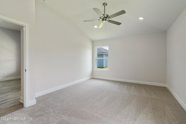 carpeted spare room featuring ceiling fan and lofted ceiling