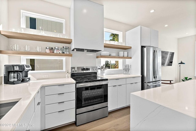 kitchen featuring appliances with stainless steel finishes, white cabinets, backsplash, light hardwood / wood-style floors, and light stone countertops