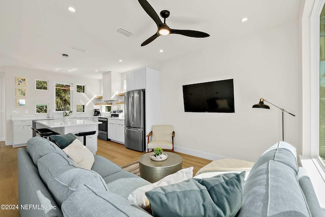 living room with light hardwood / wood-style floors and ceiling fan