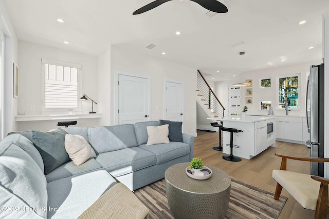 living room with ceiling fan and light hardwood / wood-style flooring