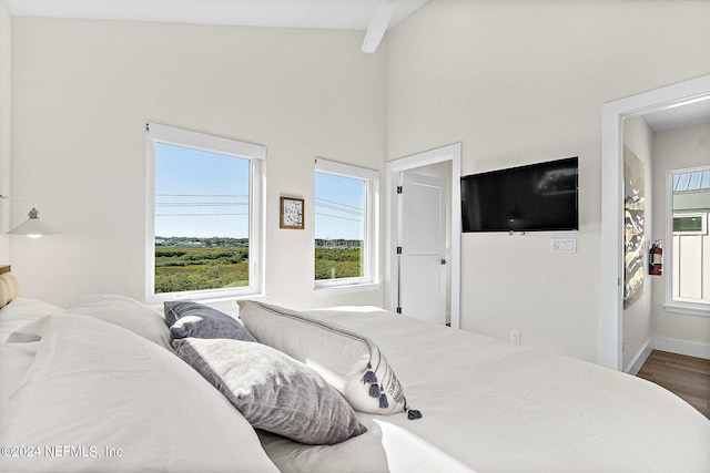 bedroom with hardwood / wood-style floors and vaulted ceiling with beams