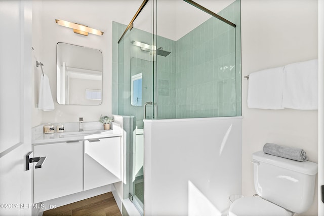 bathroom featuring hardwood / wood-style flooring, toilet, an enclosed shower, and vanity