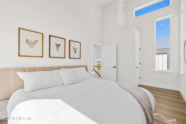 bedroom featuring a high ceiling and light wood-type flooring