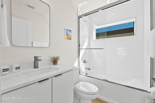 full bathroom with toilet, vanity with extensive cabinet space, and shower / bath combination with glass door