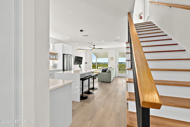 staircase with light hardwood / wood-style floors and ceiling fan