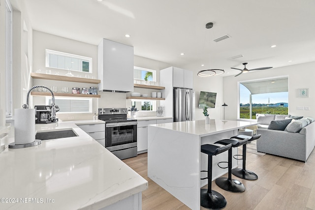 kitchen with a kitchen breakfast bar, light hardwood / wood-style floors, stainless steel appliances, and white cabinetry