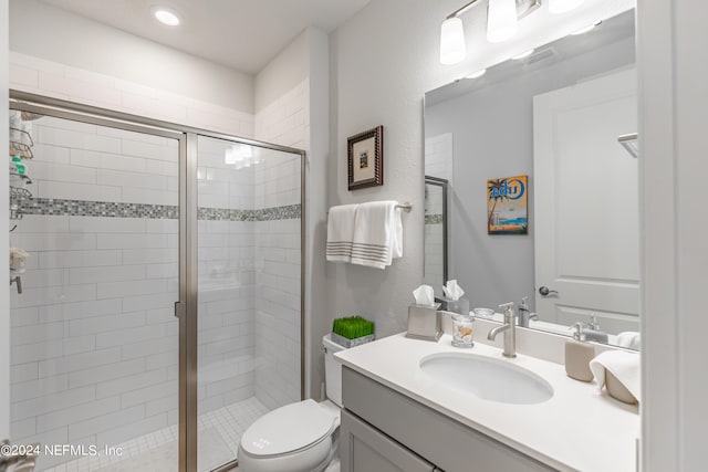 bathroom featuring a shower with door, toilet, and vanity