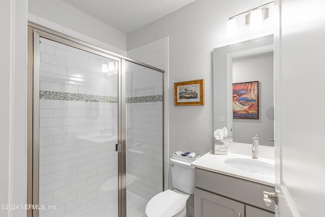 bathroom featuring toilet, vanity, and a shower with door