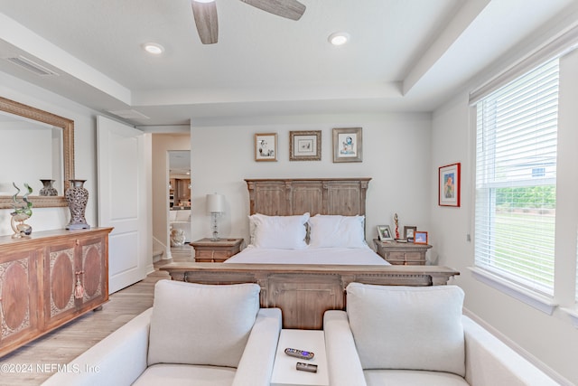 bedroom with a raised ceiling, light hardwood / wood-style floors, and ceiling fan