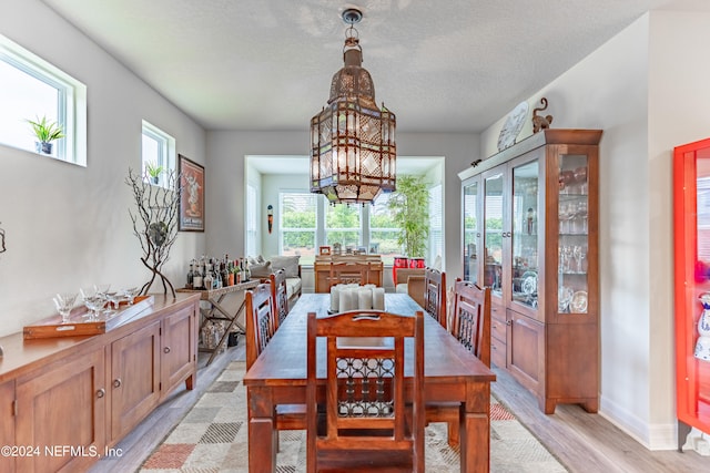 dining space with a notable chandelier, light hardwood / wood-style floors, and a textured ceiling