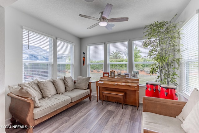 living room featuring light hardwood / wood-style floors, a textured ceiling, and ceiling fan