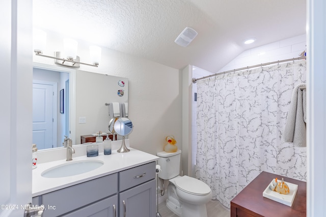 bathroom with toilet, a textured ceiling, vaulted ceiling, and vanity with extensive cabinet space