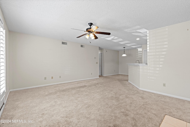 unfurnished living room with ceiling fan, a textured ceiling, and light carpet