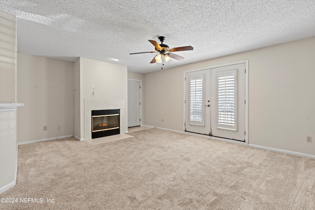 unfurnished living room featuring ceiling fan, french doors, light colored carpet, a textured ceiling, and a fireplace