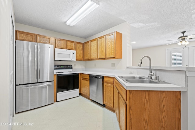 kitchen with sink, ceiling fan, a textured ceiling, appliances with stainless steel finishes, and kitchen peninsula