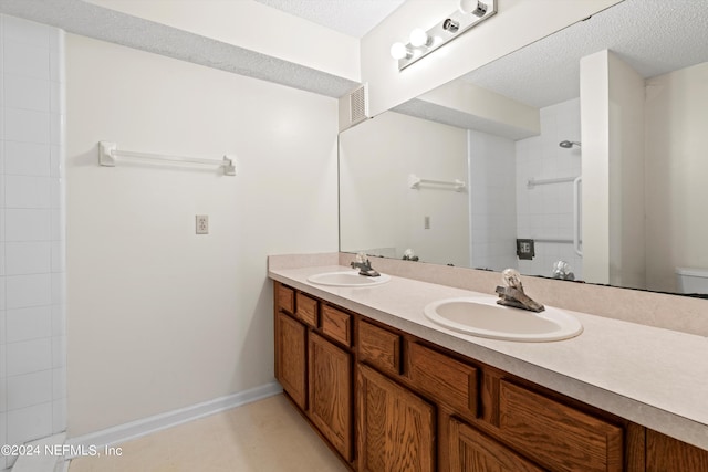 bathroom featuring a shower, vanity, a textured ceiling, and toilet