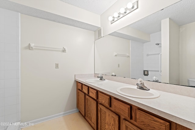 bathroom featuring vanity, a textured ceiling, toilet, and walk in shower