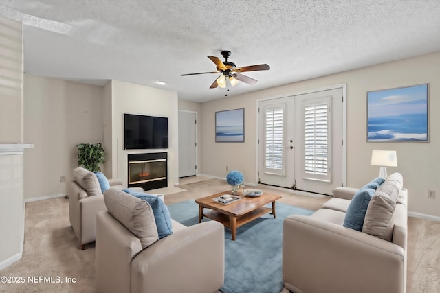 carpeted living room with ceiling fan, a textured ceiling, and french doors