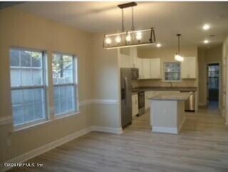 kitchen with a kitchen island, light hardwood / wood-style floors, decorative light fixtures, and white cabinetry